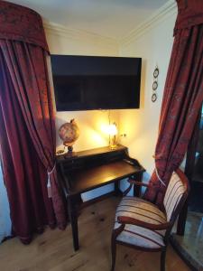 Zimmer mit einem Schreibtisch, einem TV und einem Stuhl in der Unterkunft Hotel Adler in Sankt Georgen im Schwarzwald