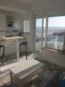 ein Wohnzimmer mit einem Tisch und eine Küche mit Fenstern in der Unterkunft studio Vue mer au cœur de malo les bains pieds dans l eau in Dunkerque