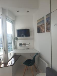 Dieses weiße Zimmer verfügt über einen Schreibtisch und einen blauen Stuhl. in der Unterkunft studio Vue mer au cœur de malo les bains pieds dans l eau in Dunkerque