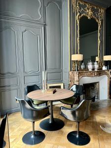una mesa y sillas en una habitación con chimenea en Luxueux 2 pièces 65m2 Hôtel Particulier XVII ième siècle-Centre Historique Clermont-Ferrand en Clermont-Ferrand