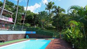 a swimming pool in front of a house with palm trees at KAZ AMOUR in Bouillante