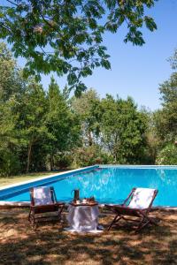 2 Stühle und ein Tisch neben einem Pool in der Unterkunft Sur la Colline in Foglia