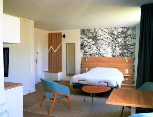 a bedroom with a bed and a table and chairs at Première Pierre in Verdelais