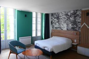 a bedroom with a bed and a chair and a table at Première Pierre in Verdelais