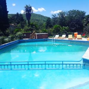 une grande piscine bleue avec des chaises et des arbres dans l'établissement Hosteria Pastoral & Spa, à La Cumbre