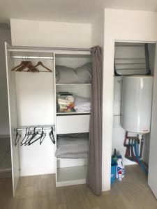 a closet with white shelves and a bed in a room at Studio tout équipé au calme in Cappelle-la-Grande