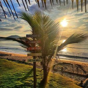 a palm tree next to a sign on a beach at Pousada Recanto Som do Mar in Caraguatatuba