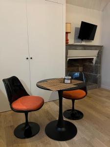 - une table et deux chaises dans une pièce avec cheminée dans l'établissement Unique et charmant 35 m2 Hôtel Particulier XVII ieme Centre Historique Clermont-Ferrand-Lucas II, à Clermont-Ferrand
