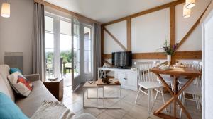 a living room with a couch and a table at Pierre & Vacances Premium Residence & Spa Houlgate in Houlgate