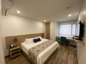 Dormitorio con cama, escritorio y TV en EcoHub Hotel Medellin, en Medellín