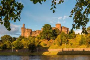 a castle sitting on top of a hill next to a lake at Stephen's Street Apartment, Inverness City Centre in Inverness +5 photos
