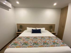 a bedroom with a large bed with a blue pillow at EcoHub Hotel Medellin in Medellín