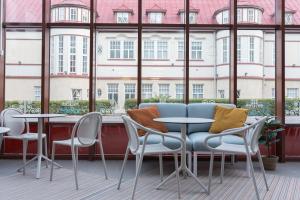 Habitación con mesas, sillas y ventana grande. en Boutique Hotel Lähde en Lappeenranta