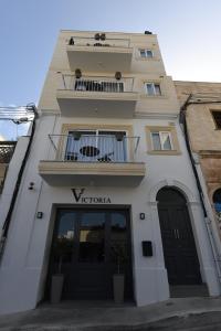 a tall white building with a balcony and a window at Victoria by Petit Chic in Mellieħa