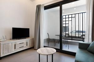 a living room with a couch and a tv and a balcony at Apartamento Virgen de la Luz 4 in Conil de la Frontera