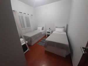um quarto branco com 2 camas e um espelho em Recanto da Madeira. em Ribeira Brava