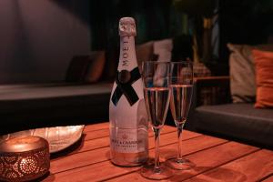 a bottle of champagne and two glasses on a table at Bed & Wellness Boxtel in Boxtel
