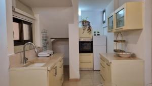 una cocina con armarios blancos y fregadero en שני חדרי שינה, חניה חינם, איזור שקט ויוקרתי,, en Rechovot