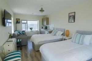 ein Hotelzimmer mit 2 Betten und einem Sofa in der Unterkunft The Gaslight Inn Holiday Apartments & Licenced Restaurant Rossnowlagh in Rossnowlagh