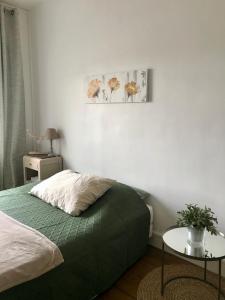 a bedroom with a green bed and a table at Esprit Cosy in Alençon