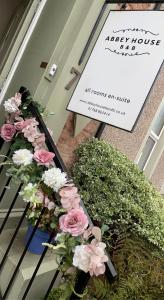 a sign with flowers in front of a building at Abbey House B & B in Penrith