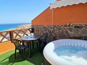 un patio con bañera de hidromasaje, mesa y sillas en El Olivar Aulaga Beach, en Puerto del Rosario