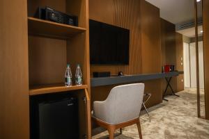 um quarto de hotel com uma cadeira e uma televisão em Urbanin Apartment & Hotel em Tirana