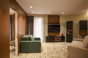 sala de estar con sofá verde y TV en Urbanin Apartment & Hotel, en Tirana