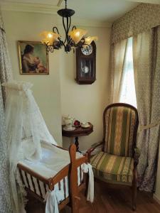 ein Schlafzimmer mit einem Kinderbett, einem Stuhl und einer Uhr in der Unterkunft Hotel Adler in Sankt Georgen im Schwarzwald