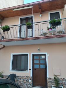 ein Haus mit einem Balkon mit einer Tür und Pflanzen in der Unterkunft Borghetto Verde in Locri