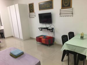uma sala de estar com uma televisão e uma mesa e cadeiras em Azin Ramli Studio em Seri Kembangan