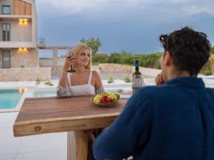 uma mulher sentada à mesa com um homem a beber vinho em Allure Wellness Retreat em Lefkada