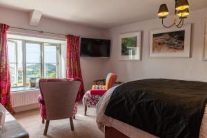 um quarto com uma cama e cadeiras e uma televisão em West Lyn Farm em Lynton