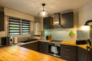 une cuisine avec des placards gris et un comptoir en bois dans l'établissement 100 Genève joli T2 avec place de parking privée, à Annecy