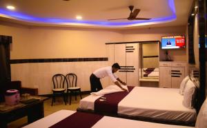 a man making a bed in a hotel room at Ananya Hotel in Digha