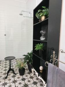 a bathroom with a black shelf with plants and a stool at Daisy Place in Franschhoek