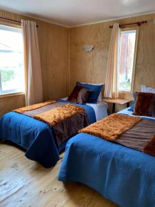 um quarto com 2 camas com lençóis azuis e castanhos em Queltehues natural em Castro