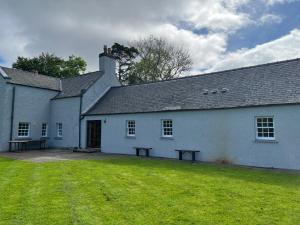 a white building with a picnic bench in front of it at Sherrabeg Cottage in Newtonmore