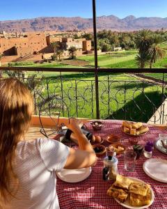 a woman sitting at a table with a plate of food at Riad Al Anwar in Tinerhir