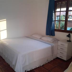 a bedroom with a white bed and a window at Casa agradável in Cabo Frio