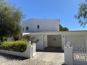 une maison blanche avec un portail et un garage dans l'établissement Vivenda Júlia e Tavares, à Vilamoura