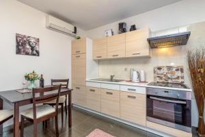 a kitchen with wooden cabinets and a table and a dining room at Apartments Kardumovic in Poreč
