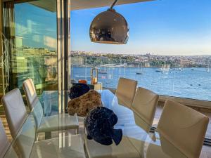 a dining room table with chairs and a view of the water at Seafront Duplex Penthouse in Sliema