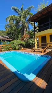 a blue swimming pool on a wooden deck with a palm tree at Canoa Abraão in Abraão