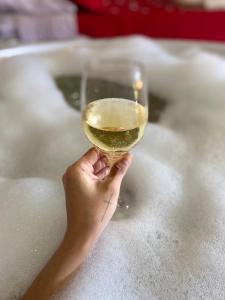 a person holding a glass of wine in a bath tub at Canoa Abraão in Abraão