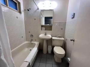 a bathroom with a sink and a toilet and a tub at Motel Du Chevalier in Gatineau
