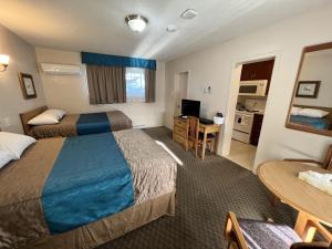a hotel room with two beds and a table at Motel Du Chevalier in Gatineau