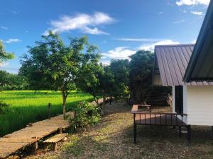 una casa con un banco delante de un campo en Pua Na Nan Camping ปัวนาน่านแคมป์ปิ้ง, en Pua