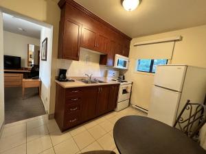a kitchen with wooden cabinets and a white refrigerator at Motel Du Chevalier in Gatineau