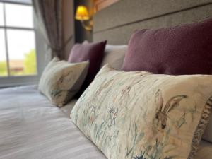 a bed with three pillows and a pillow with a spider on it at The Jug And Bottle in Heswall